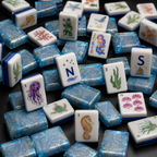 Ocean-themed mahjong tiles scattered on a black surface with upright seaweed, jellyfish, wind, Joker, and seahorse tiles.