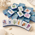 Ocean-inspired mahjong tiles styled on a cream background with a curved row of mermaid Joker, wind, seaweed, seahorse, clownfish, and jellyfish tiles.