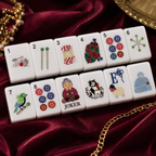 White craft-inspired mahjong tiles displayed in two rows on burgundy satin with elegant gold accessories