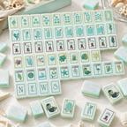 Set of mahjong tiles with various symbols on a light surface.