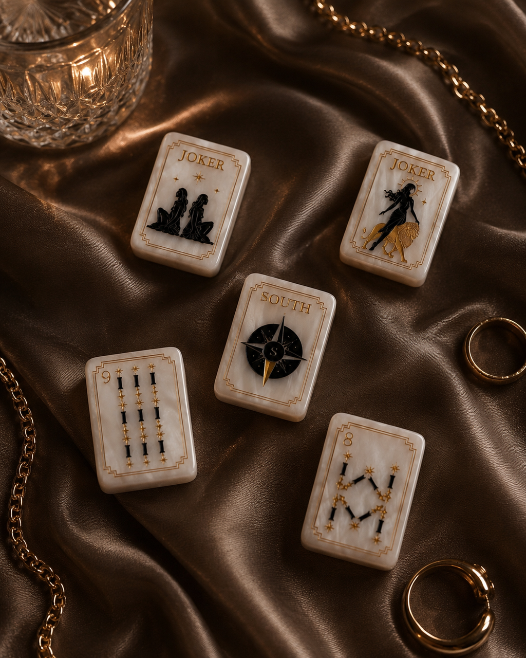Celestial Mahjong tile collection scattered across brown satin with gold jewelry