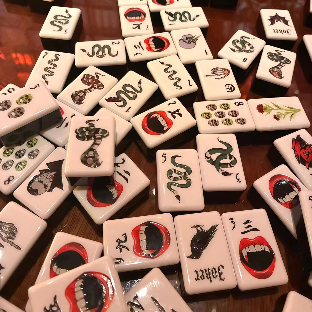 A gothic-inspired mahjong tile set made for Halloween game nights, dark fantasy collectors, and players who want a bold alternative to traditional mahjong tiles. The design includes snakes, skulls, vampire teeth, spiders, bats, roses, and gothic-style jokers on a soft pink tile base.