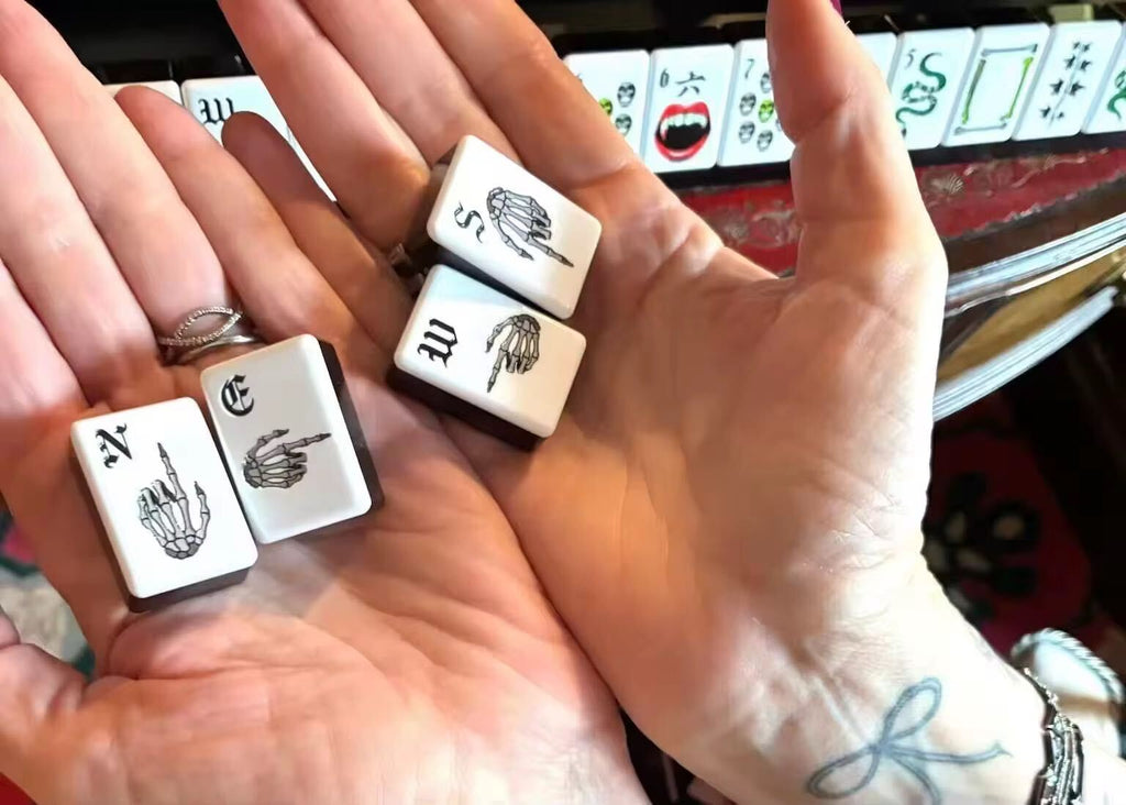 A gothic-inspired mahjong tile set made for Halloween game nights, dark fantasy collectors, and players who want a bold alternative to traditional mahjong tiles. The design includes snakes, skulls, vampire teeth, spiders, bats, roses, and gothic-style jokers on a soft pink tile base.