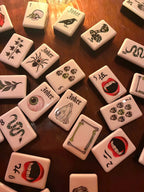 A gothic-inspired mahjong tile set made for Halloween game nights, dark fantasy collectors, and players who want a bold alternative to traditional mahjong tiles. The design includes snakes, skulls, vampire teeth, spiders, bats, roses, and gothic-style jokers on a soft pink tile base.