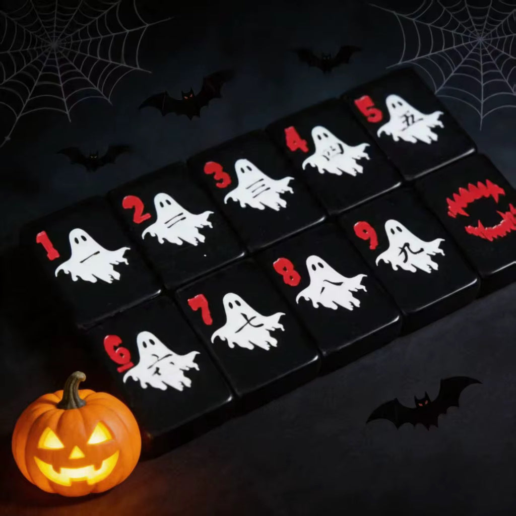 Close-up of black mahjong tiles featuring white ghost illustrations and red numbers beside a glowing jack-o’-lantern.