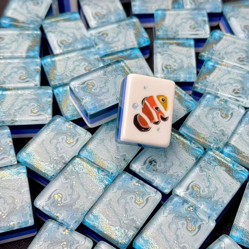 Clownfish mahjong tile displayed upright on a pile of glossy blue marbled tiles.